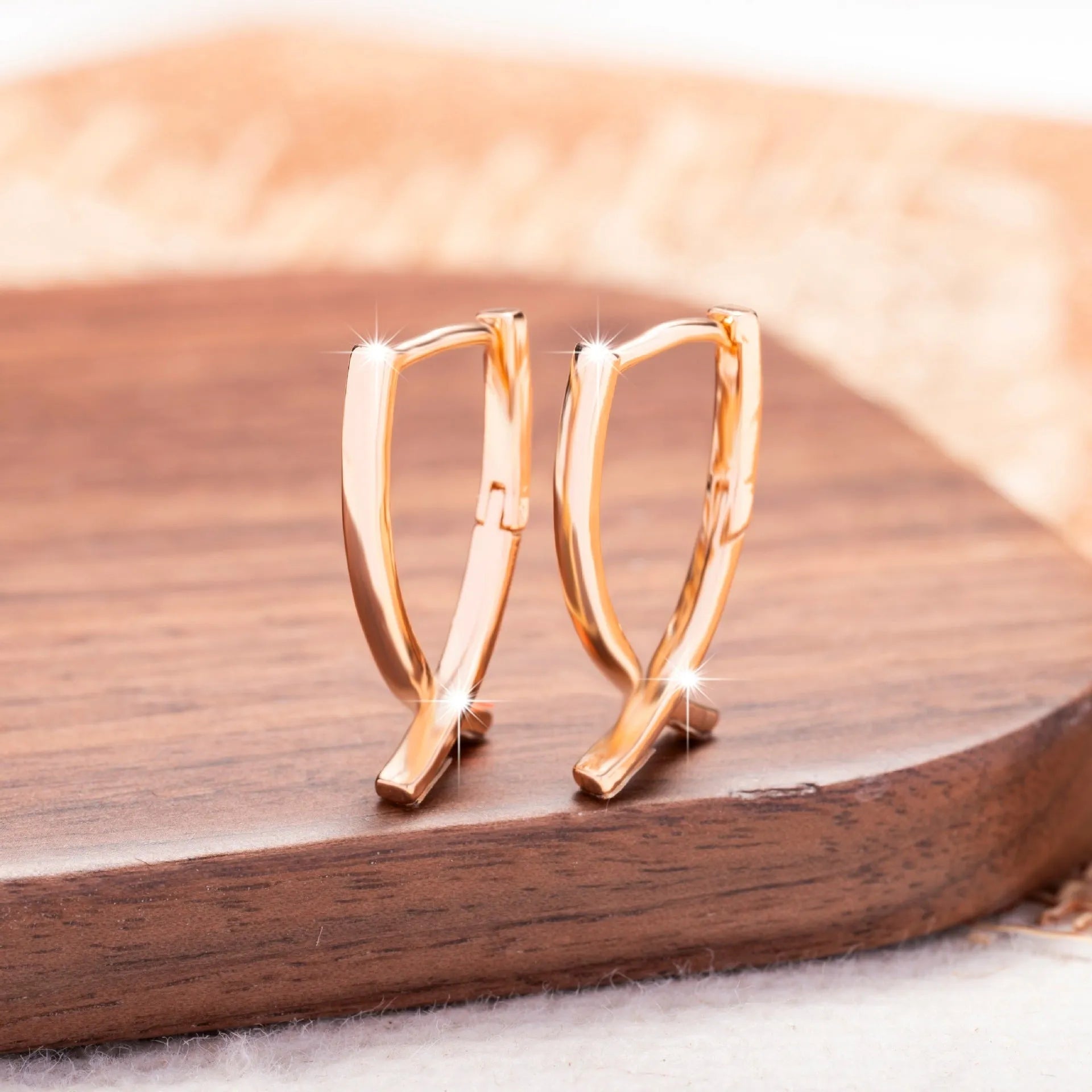 Rose gold cross shaped fashion earrings made from copper on a white background