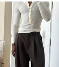 Men's cream-coloured ribbed long sleeve henley top with a button placket on a hanger.