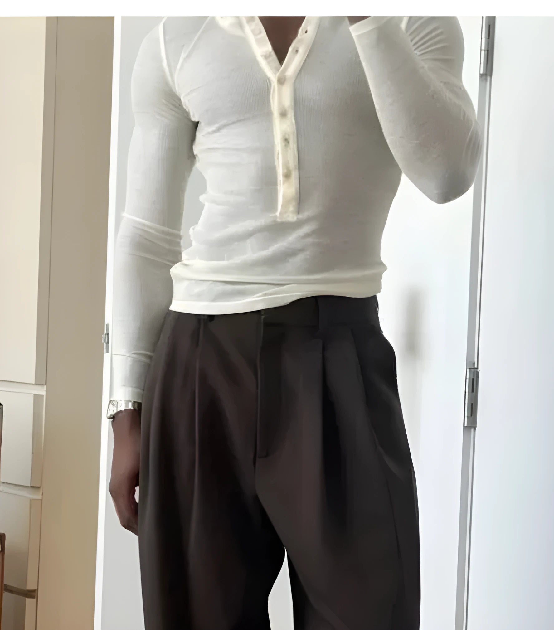 Men's cream-coloured ribbed long sleeve henley top with a button placket on a hanger.