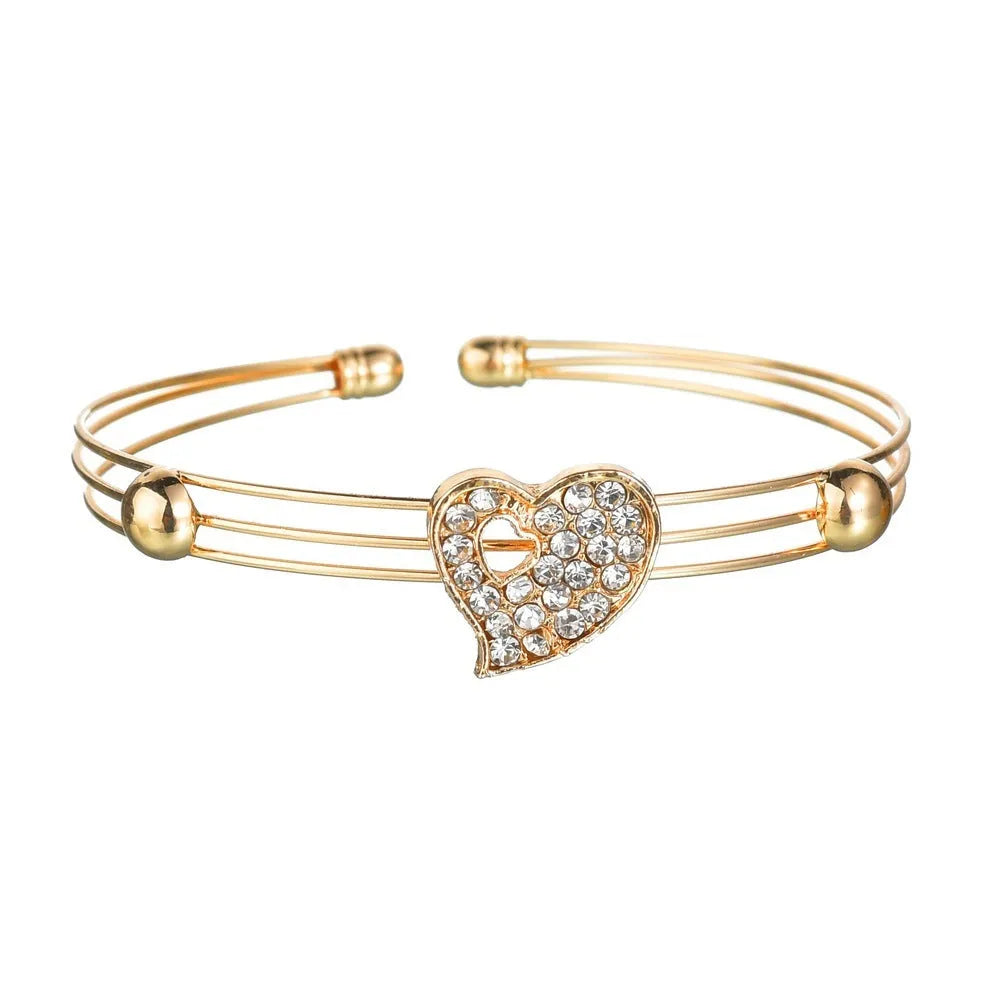 Gold women's jewellery set featuring earrings, an adjustable necklace, and a bracelet with heart, water drop, and bell pendants.