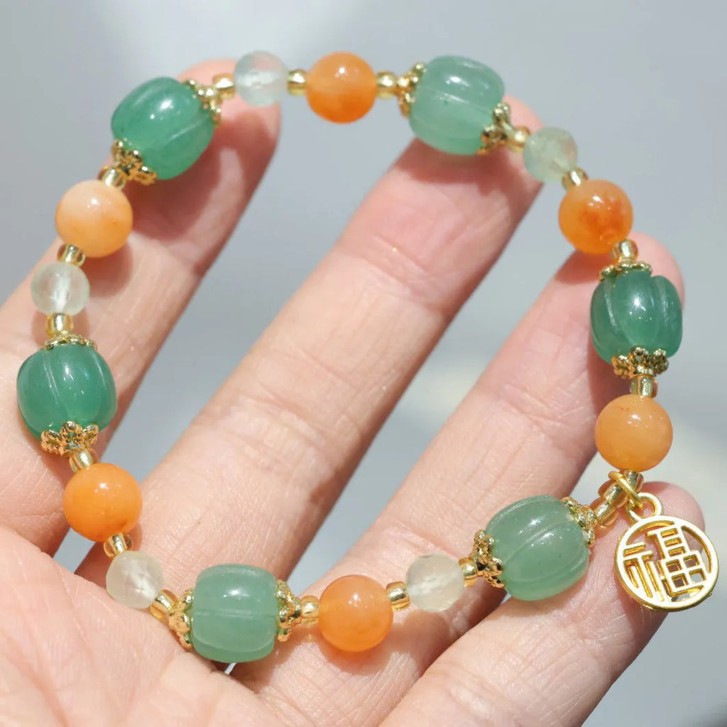 Jinsi Jade Duobao pumpkin bracelet with Prehnite bead on a flat surface, showing carved pumpkin bead and spacer beads