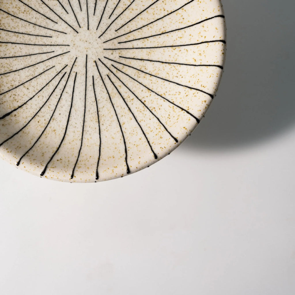 Black and white striped plastic resin dessert plate on a table.