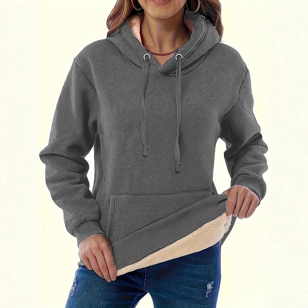 Woman wearing a thick grey hooded sweater with a 3D pattern and front pockets