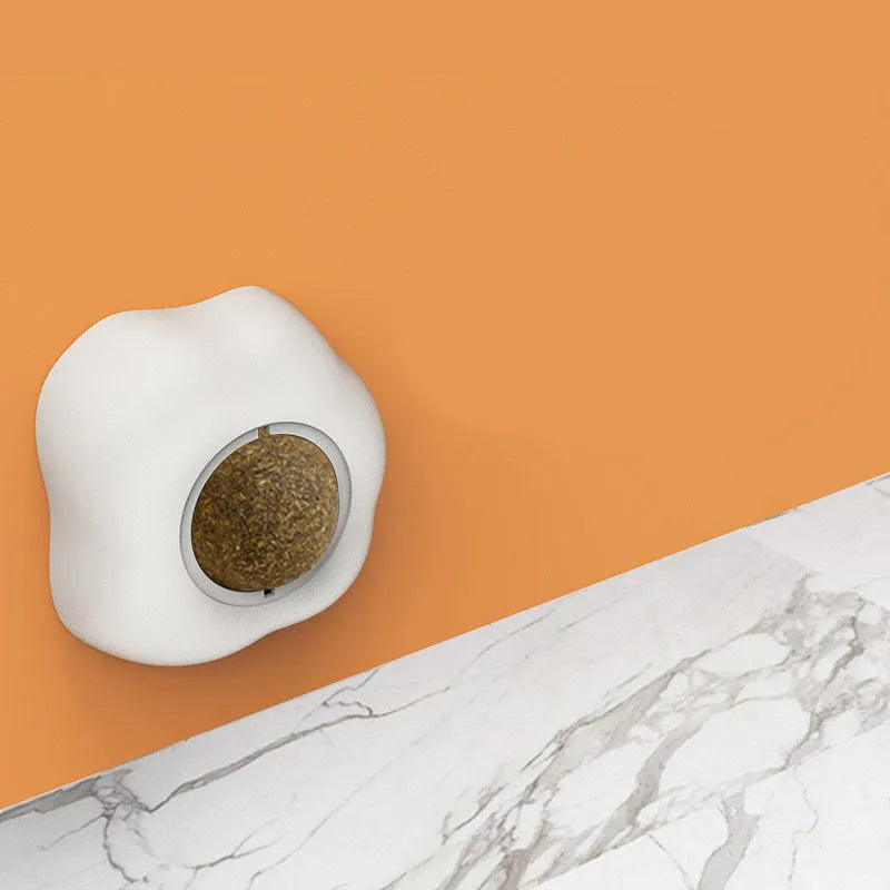 Interactive catnip ball toy with soft plush exterior mounted on wall for feline play