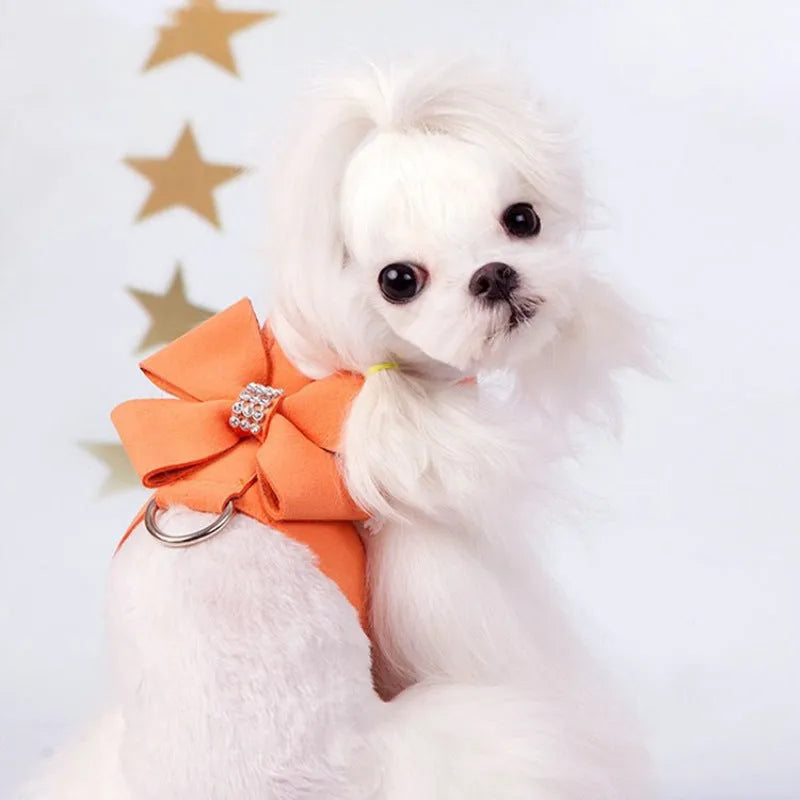 A pink microfiber dog chest strap with a large decorative bowknot, showing leash attachment ring.