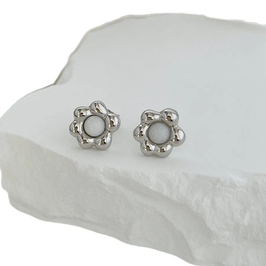 S925 sterling silver black agate flower ear studs in gold colour on a woman's ear