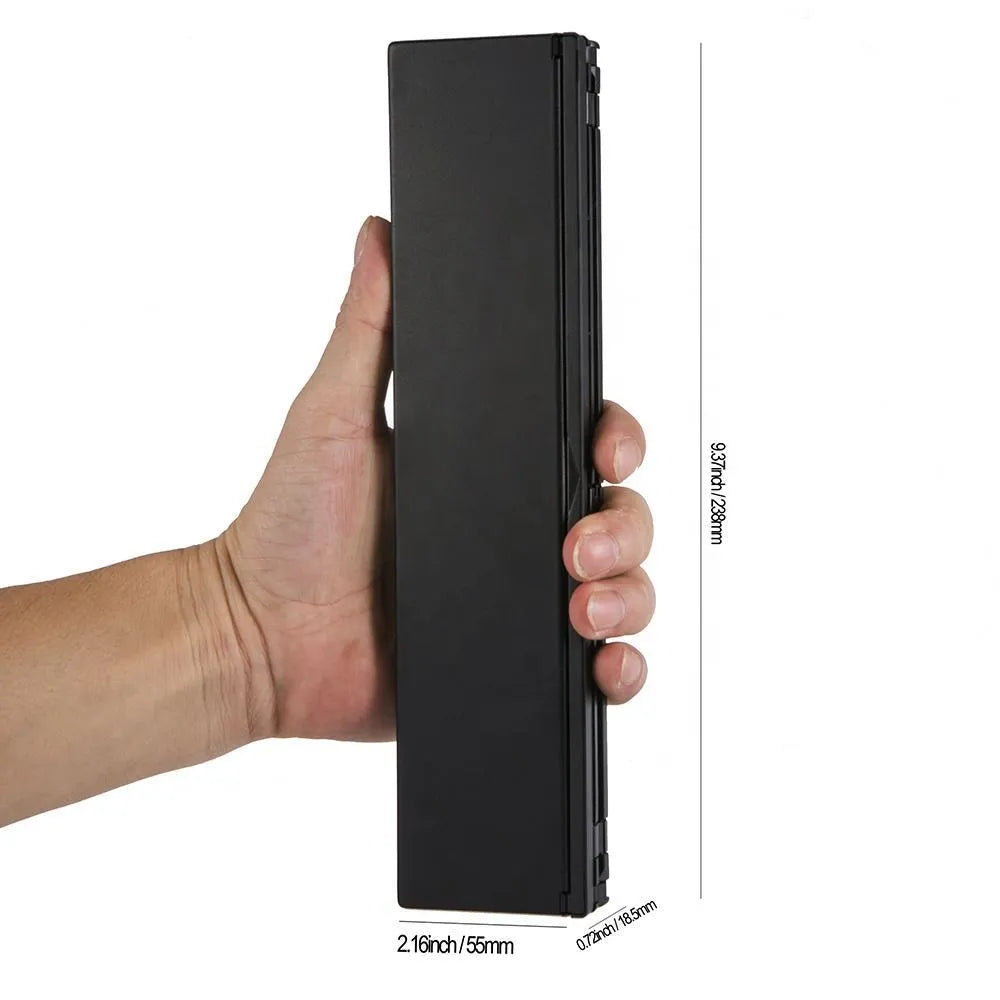 Black folding wireless Bluetooth keyboard shown open next to a tablet demonstrating its compact portable size.