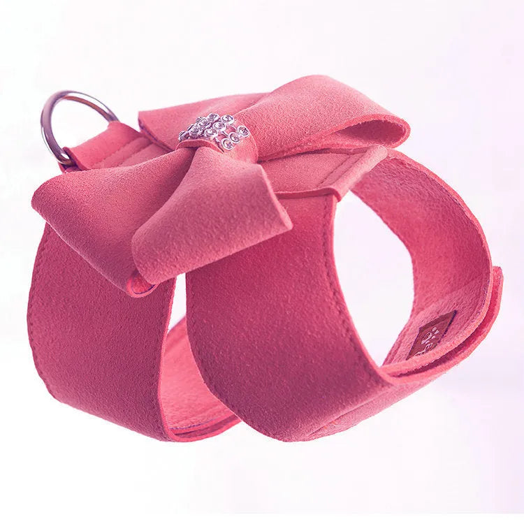 A pink microfiber dog chest strap with a large decorative bowknot, showing leash attachment ring.