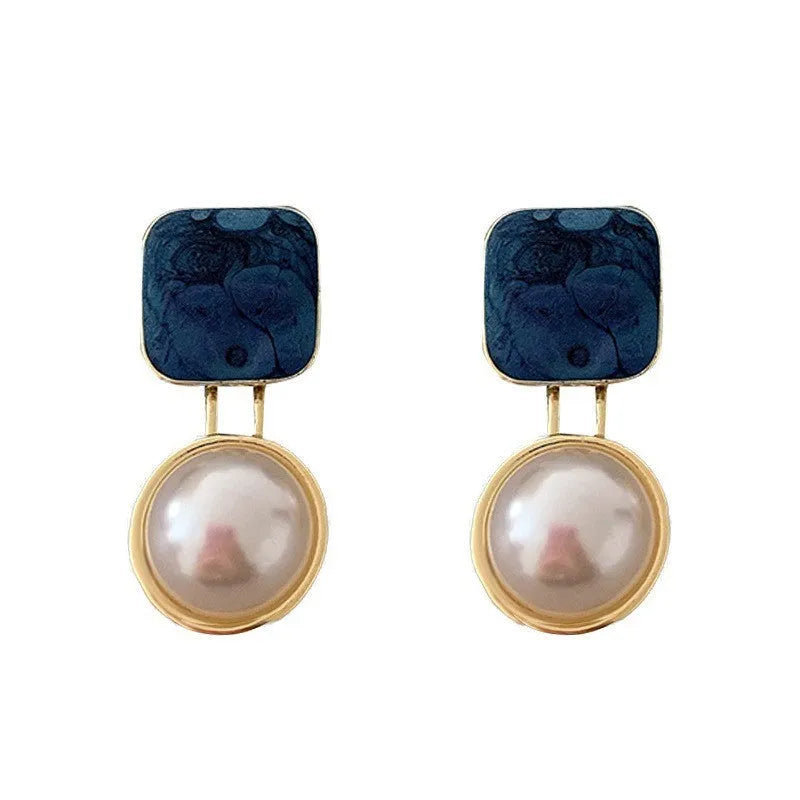Red geometric alloy stud earrings with pearl centre on white background