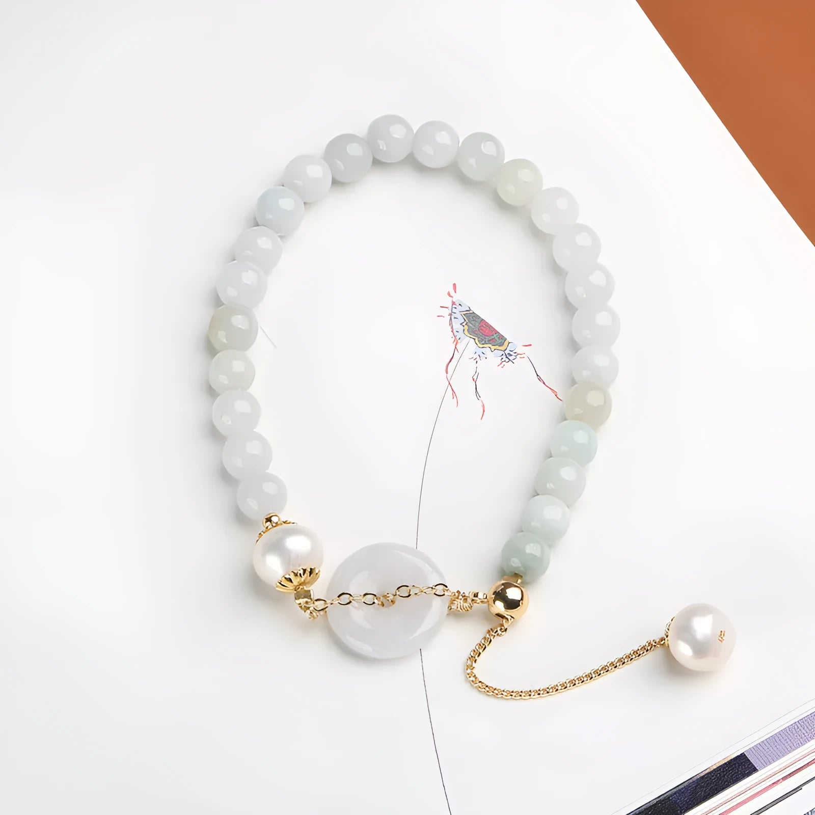 Natural emerald green jade and pearl bracelet with a geometric peace buckle clasp.