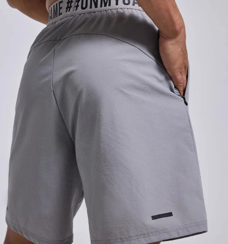 Men's loose grey cropped sports shorts with letter detailing and an elastic fly opening.