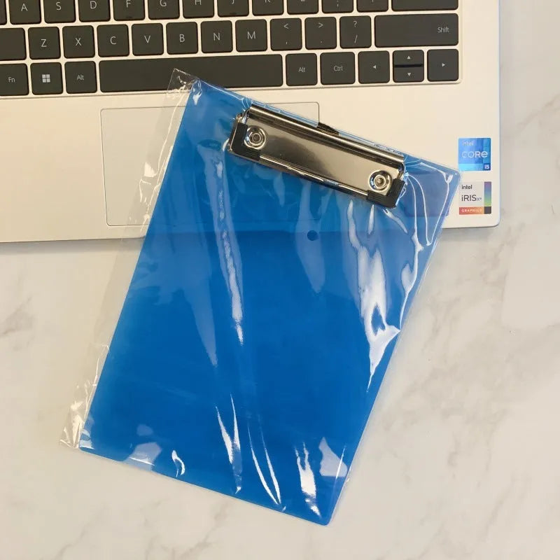 Transparent A4 plate holder with metal clip in blue, holding white paper, on a wooden desk.