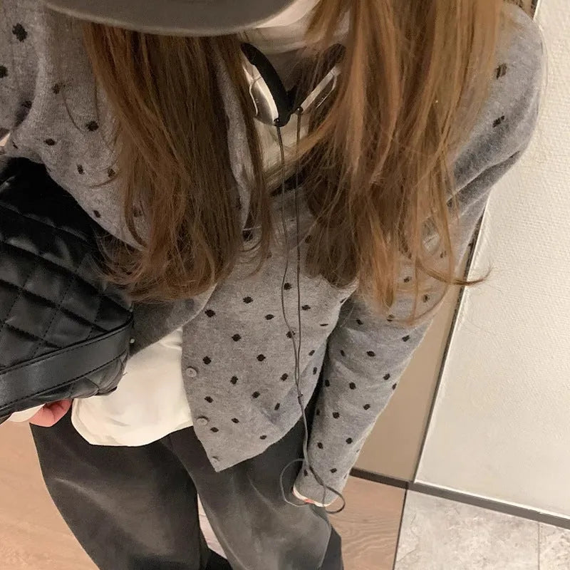 Women's grey loose-fit knitted cardigan with long sleeves on a hanger.