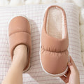 Pair of down cotton winter slippers with artificial leather upper, plush lining, and thick rubber sole.