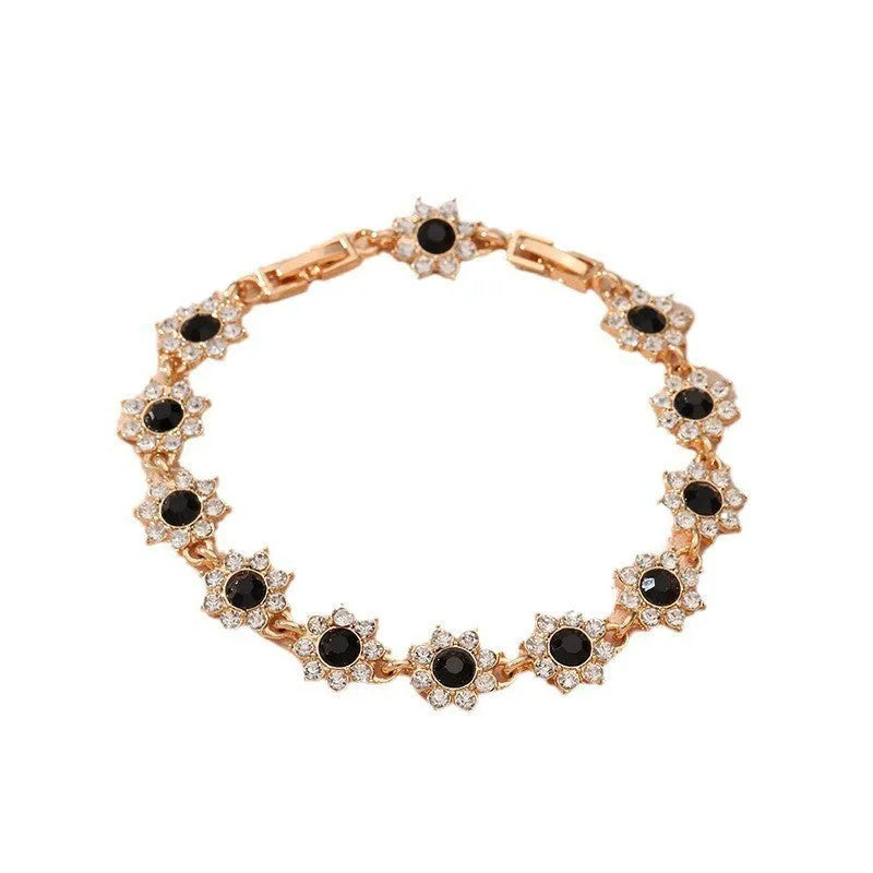 Floral shaped zinc alloy bracelet with electroplated silver finish and red coloured gemstones.