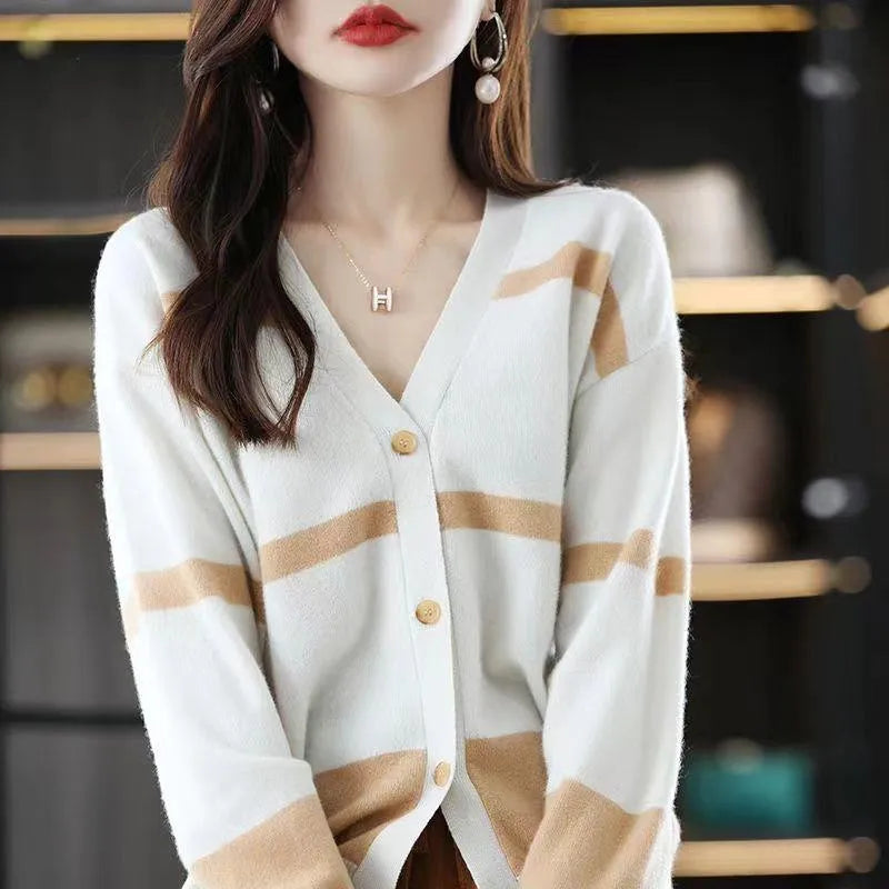 A woman wearing a slim-fit black and white striped V-neck knitted cardigan.