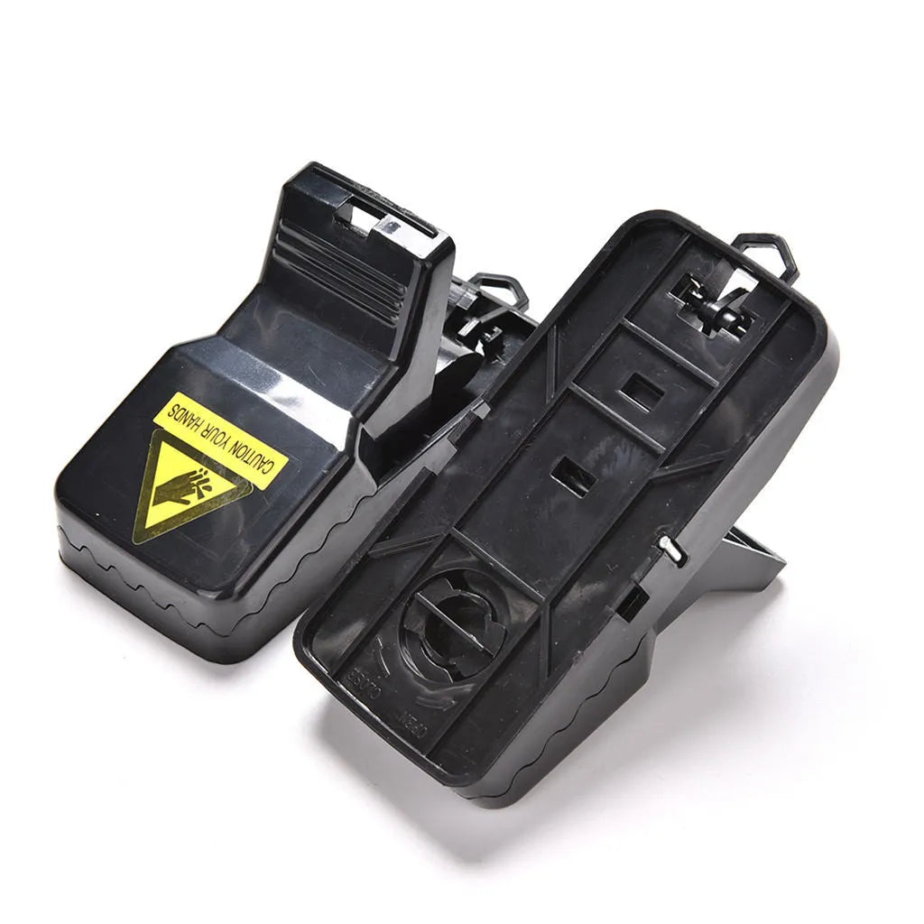Set of six black plastic snapping mousetraps with smooth surfaces, shown next to a ruler for scale.