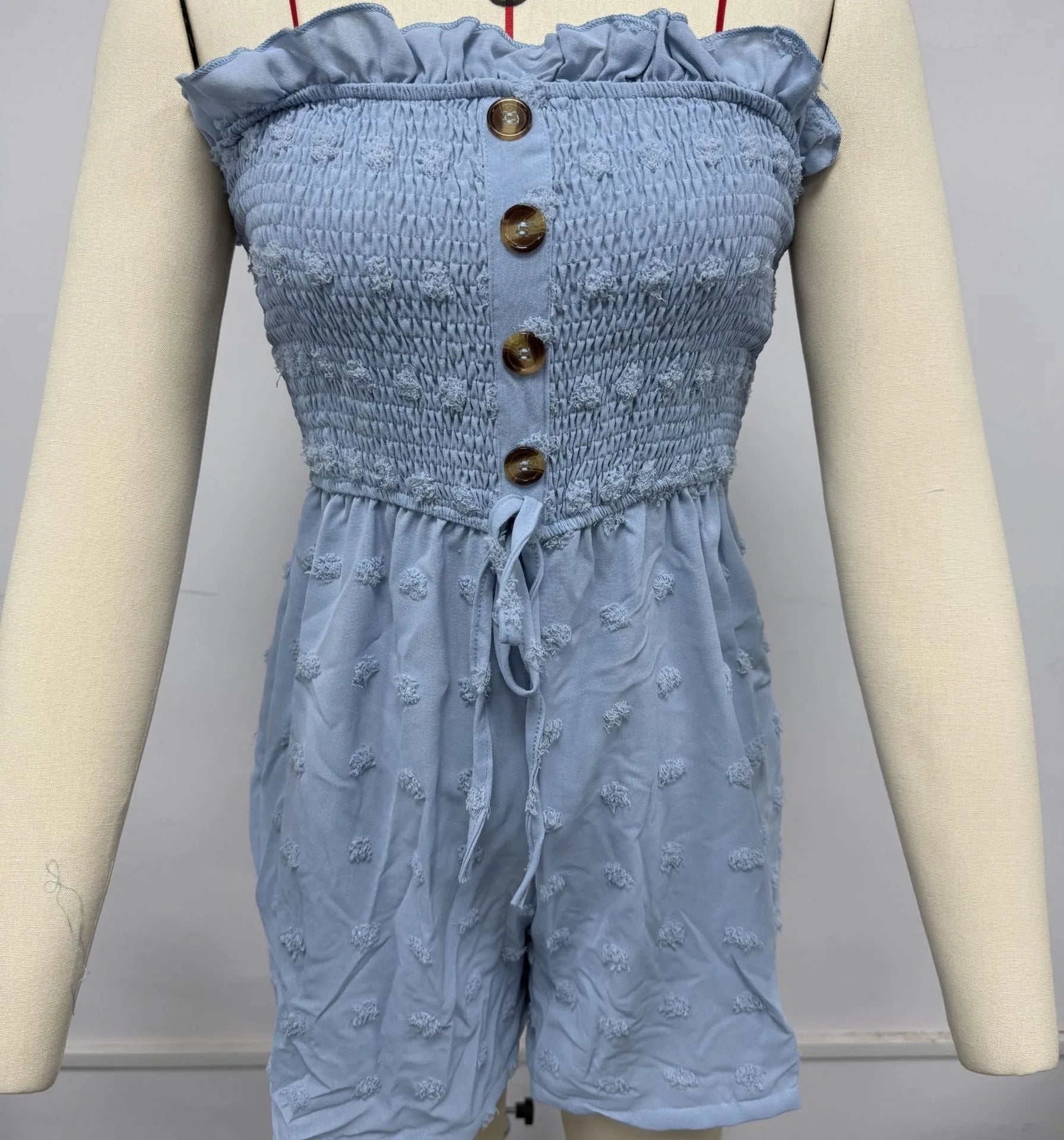 Women's sleeveless off-shoulder jumpsuit in polyester fabric showing button detailing and elastic waist