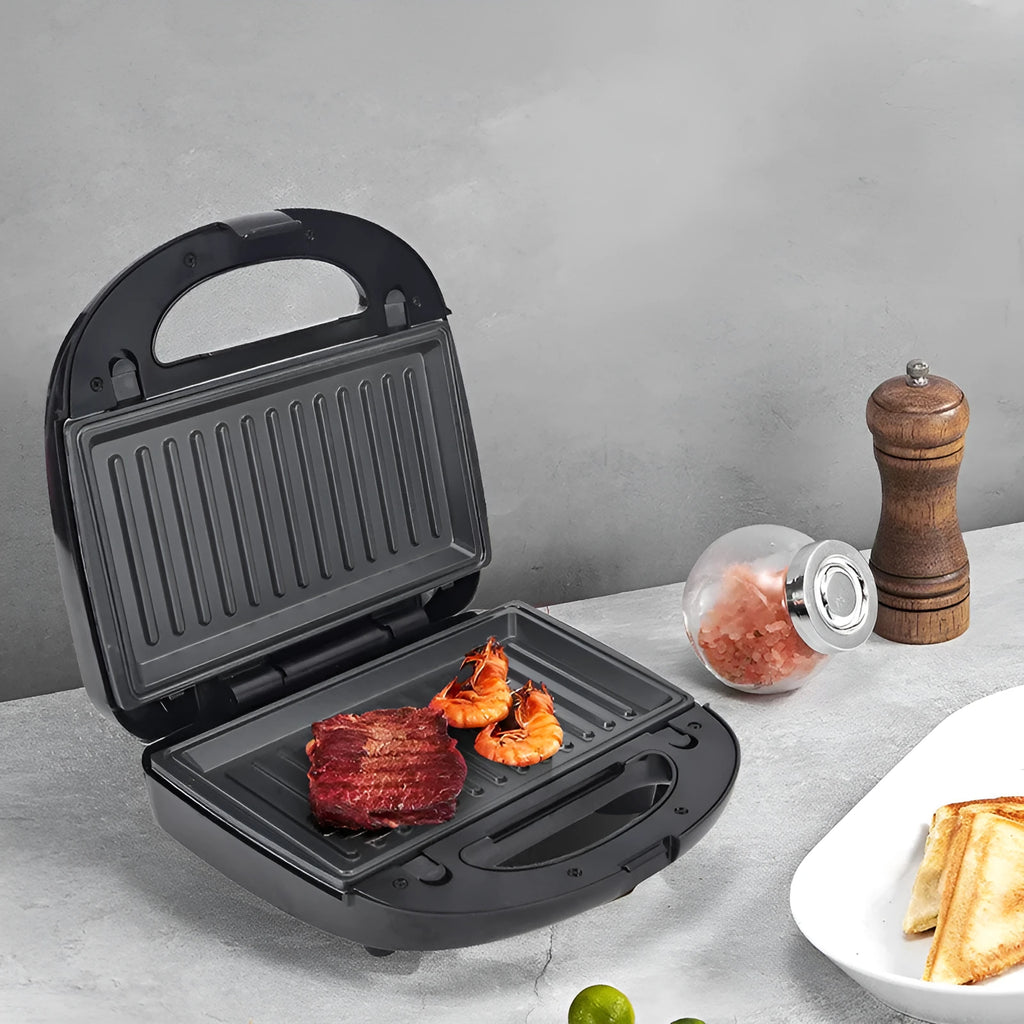 Black double-sided electric sandwich pan with stainless steel lid on a kitchen counter