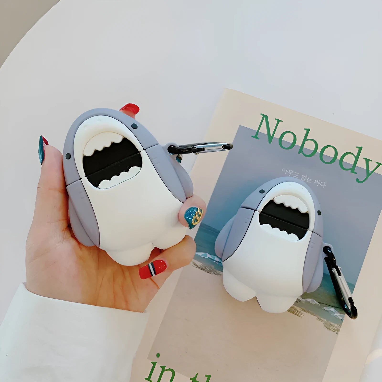 Soft silicone cover with shark fin design on a white Apple Airpods 1 wireless earbud.