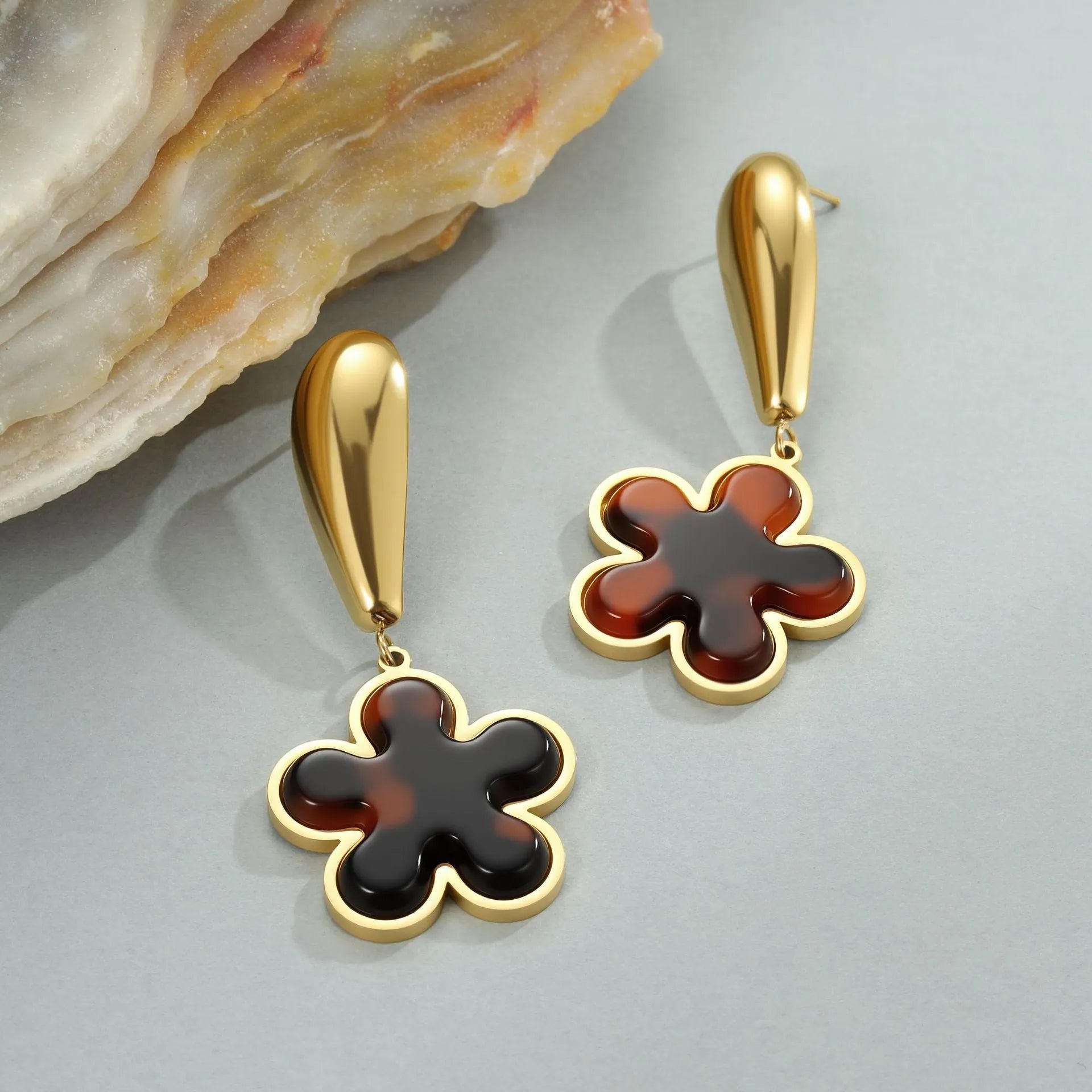Close up of 18K gold plated stainless steel earrings featuring tortoiseshell resin in heart and flower geometric shapes for women.