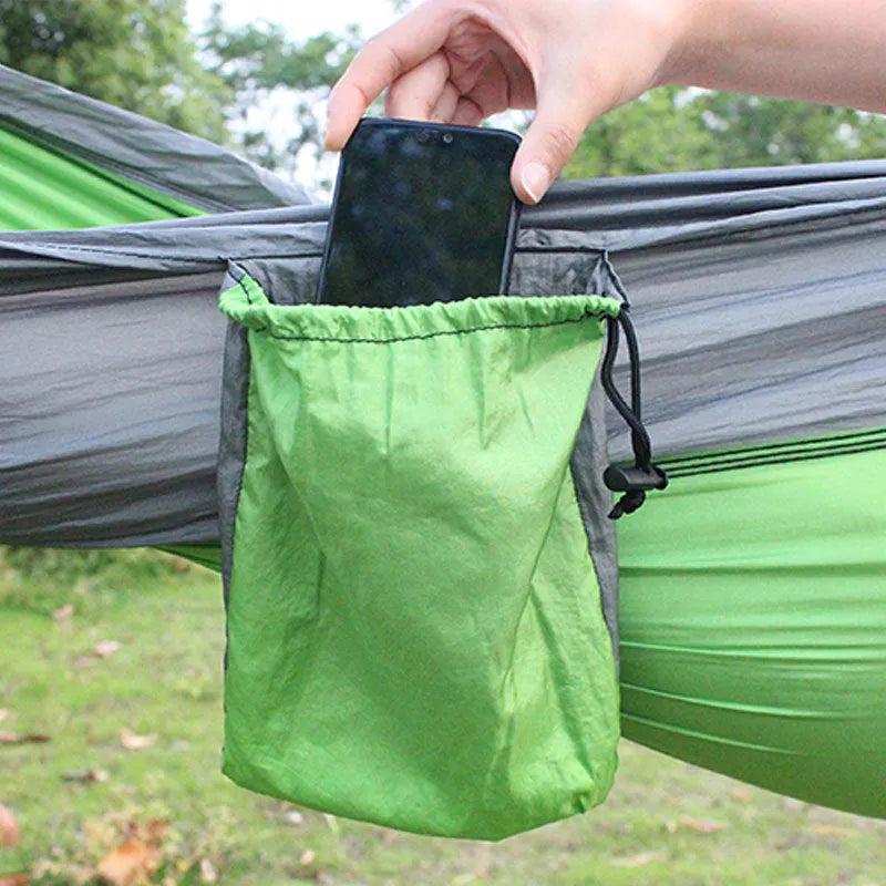 Blue outdoor camping hammock hanging between trees with ropes and carabiners