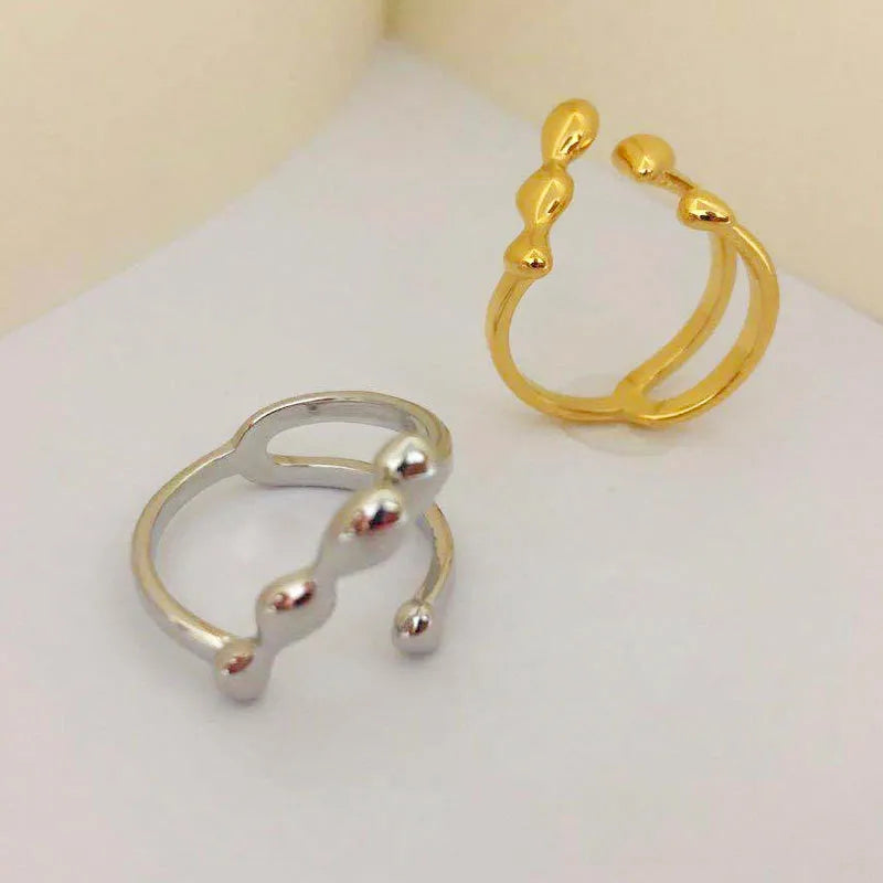 Brass opening ring with spherical details in gold or silver colour on display surface