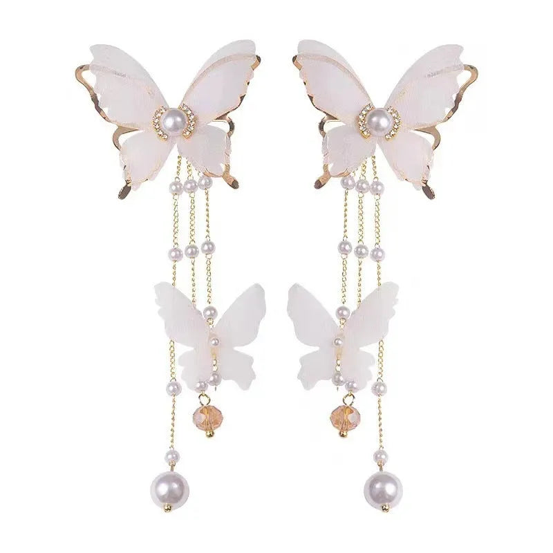 White butterfly-shaped earrings with lace patterns, pearl accents, rhinestone details, and tassel elements on copper alloy