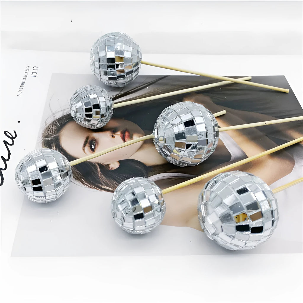 Small glass mirror disco ball on a wooden stick used as a cake decoration