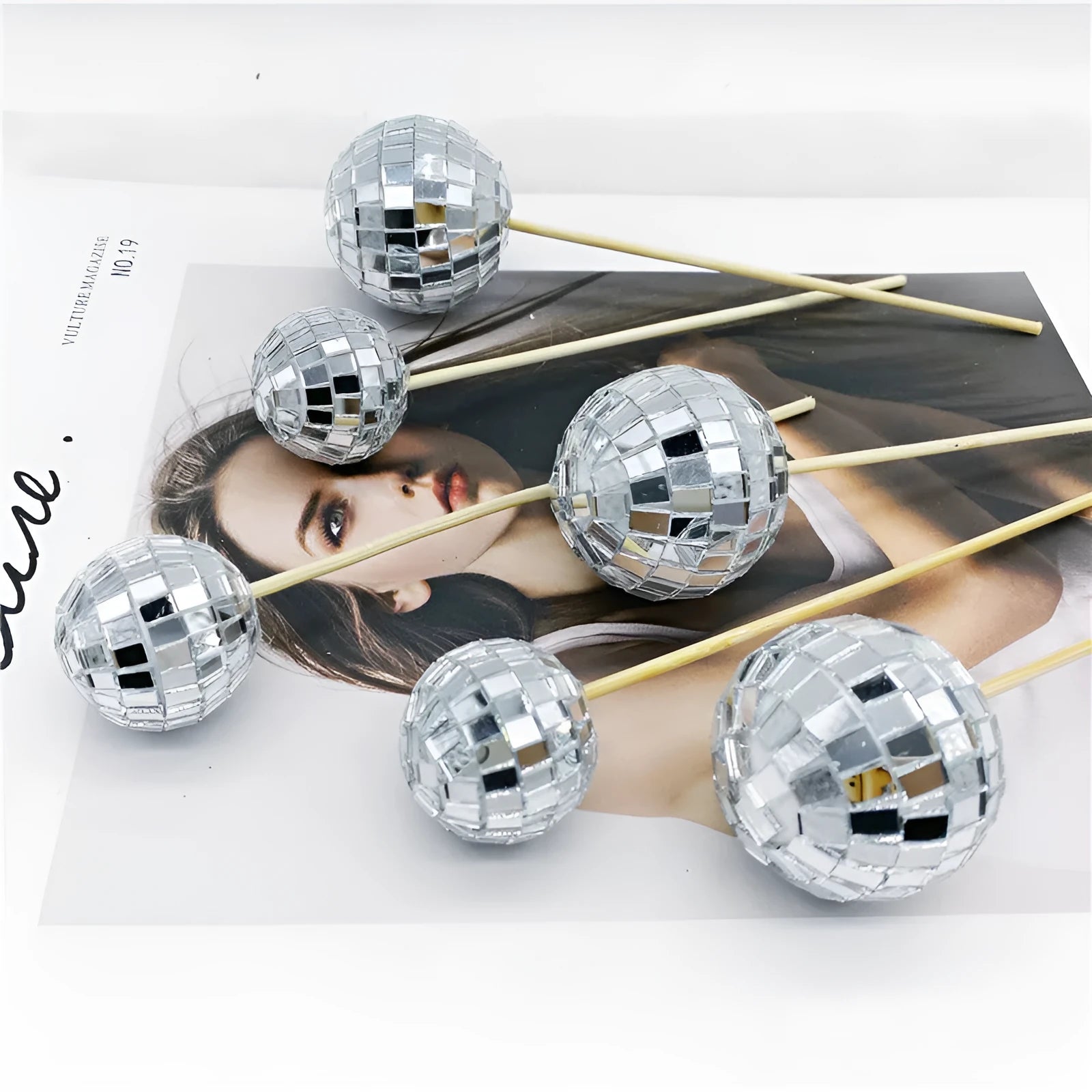 Small glass mirror disco ball on a wooden stick used as a cake decoration