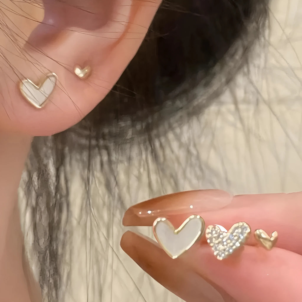 Three pairs of women's heart-shaped alloy earrings in electroplated gold, black, black-white, or pink colours