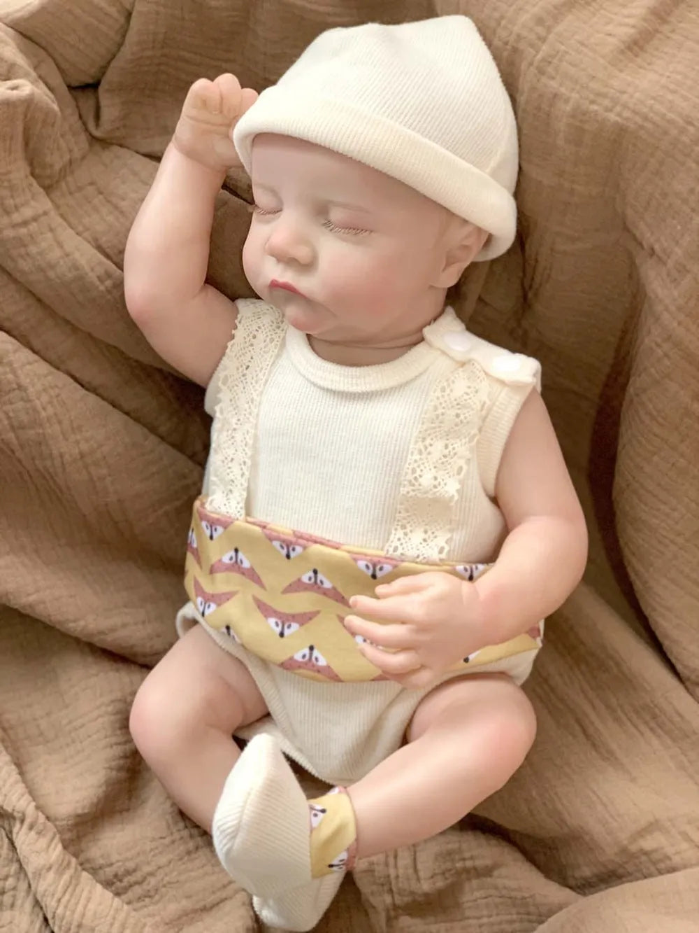 18-inch reborn doll with cloth body in soft pink romper sitting on table