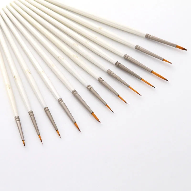 12 pearl white handled artist brushes with nylon wool bristles, stored upright in a solid wood pen holder.