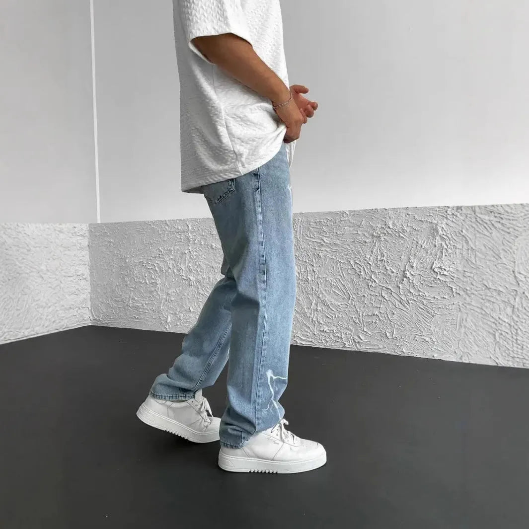Men's blue straight-leg cotton denim trousers with a wide-leg fit and five-pocket design on a neutral background.