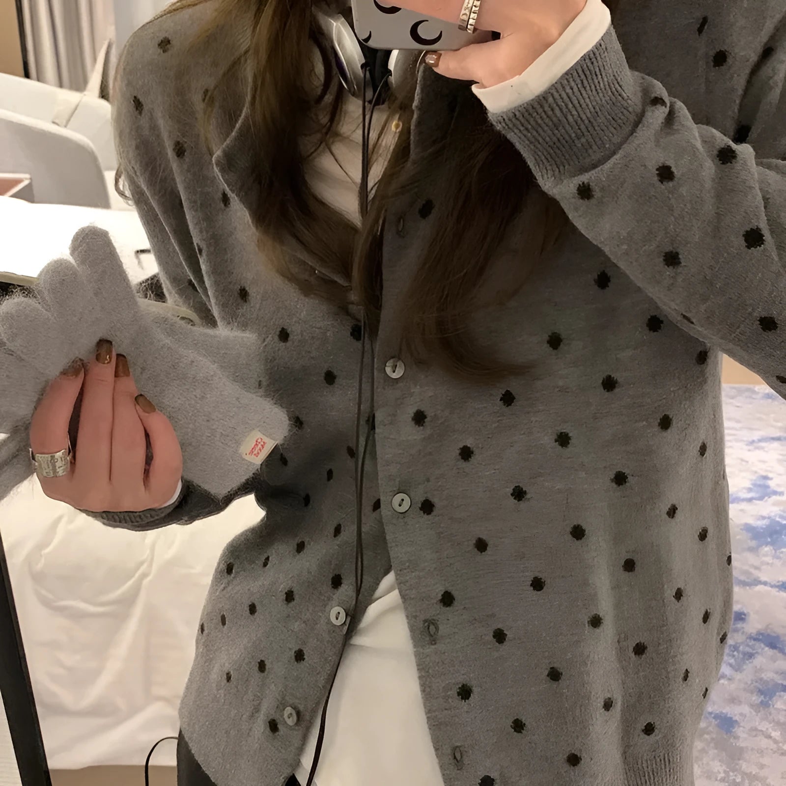 Women's grey loose-fit knitted cardigan with long sleeves on a hanger.