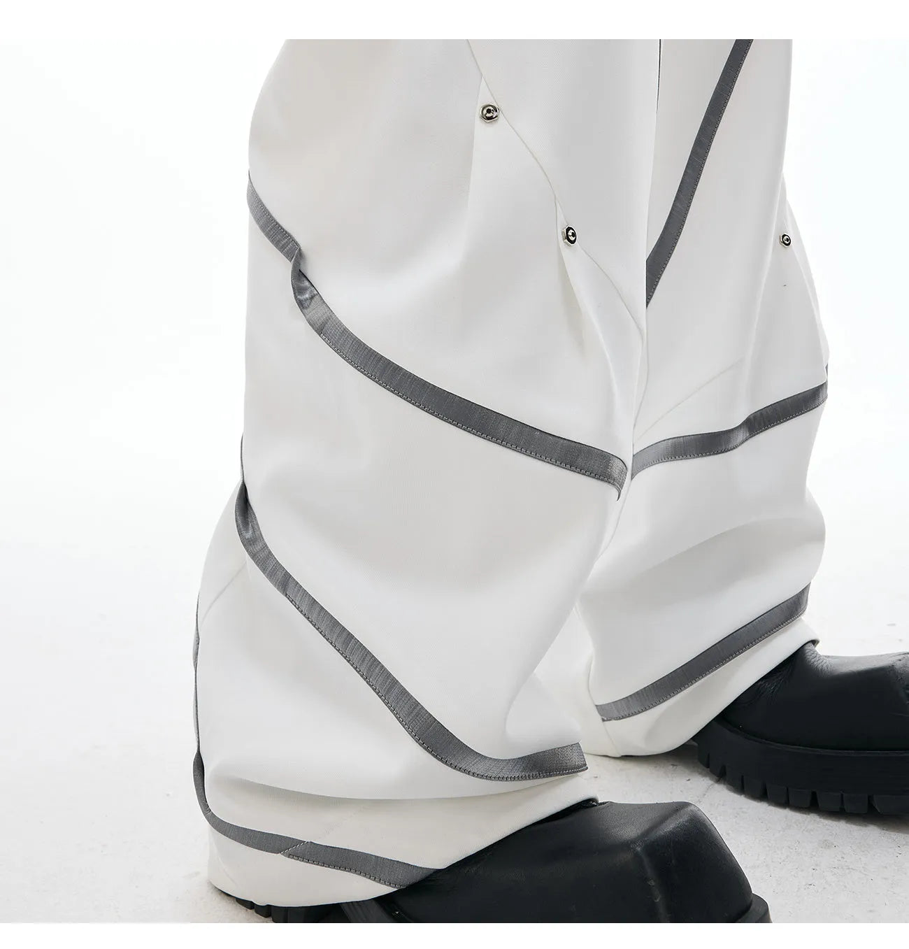 Men's polyester trousers with metal rivet accents and pleated detailing on three-dimensional cutting construction