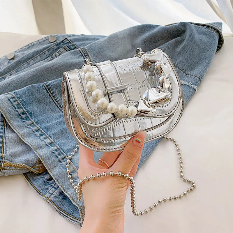 Silver laser pearl finish women's crossbody mini saddle tote bag with single shoulder strap.