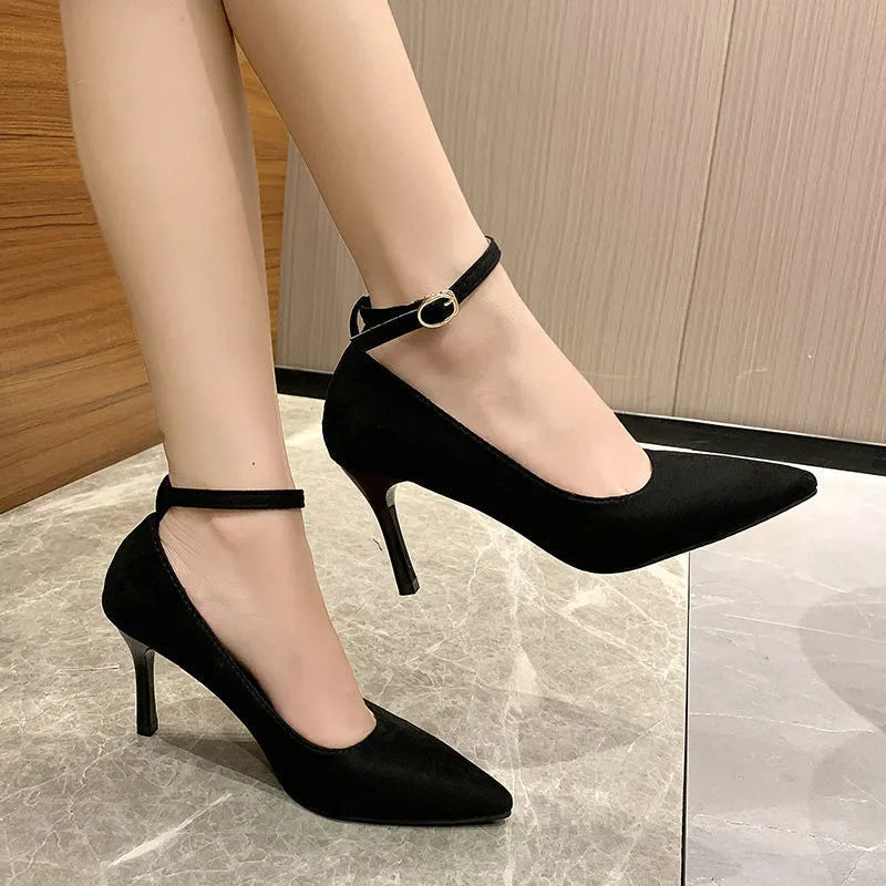 Women's black stiletto pump shoe with a decorative buckle and skull pattern on the toe.