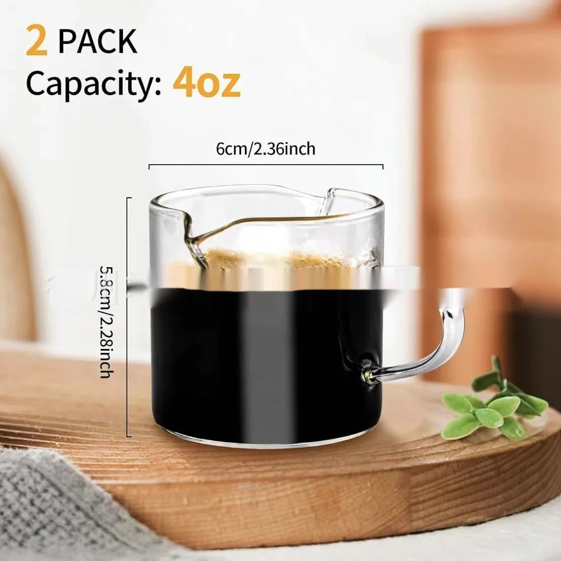 Two white modern double mouth transparent glass coffee cups on a table.