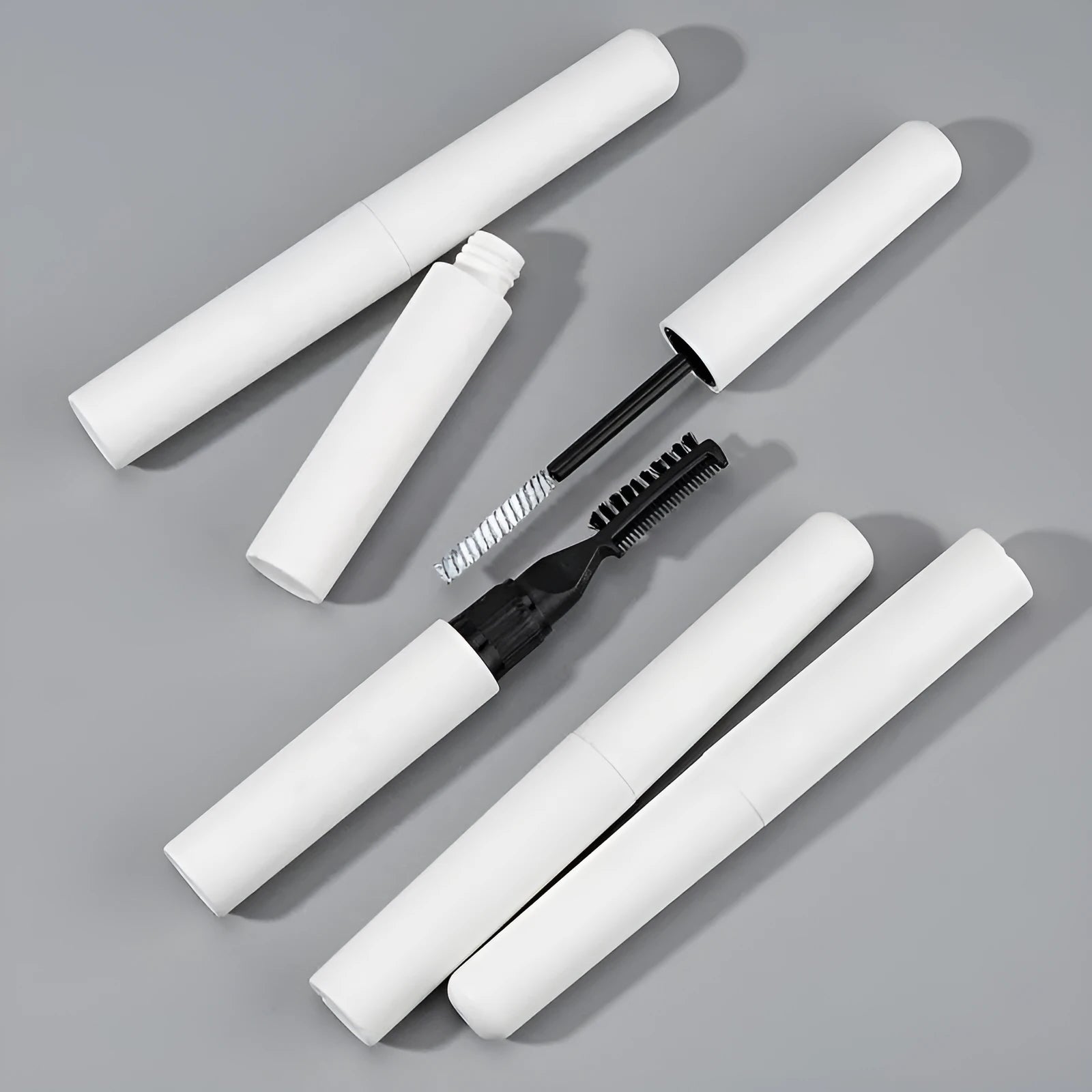 Eyebrow mould shaping brush and bottle of liquid eyebrow glue in pink or white.
