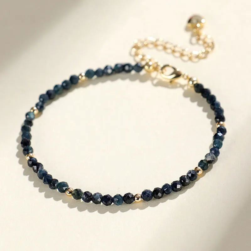 Close-up of a women's bracelet with small blue tourmaline beads and spacer beads on a wrist.