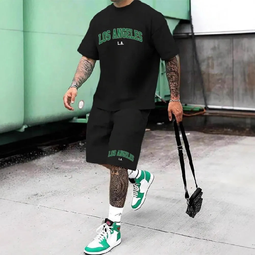Man wearing a men's short sleeve top and shorts set with a 3D printed letter design, in a sportswear setting.