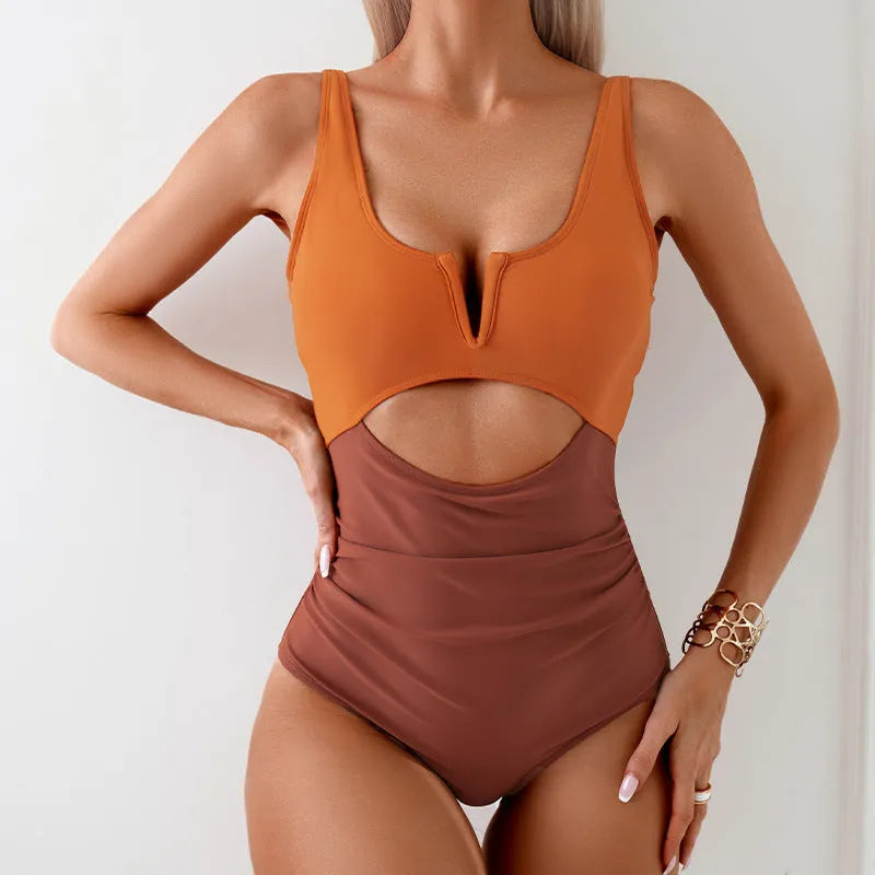 Women's one-piece swimsuit in a colour block pattern, shown in green, on a mannequin.