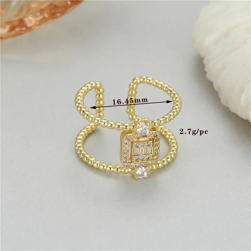 Gold-plated copper adjustable open ring with an asymmetric U-shaped design on a flat surface.