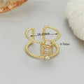 Gold-plated copper adjustable open ring with an asymmetric U-shaped design on a flat surface.