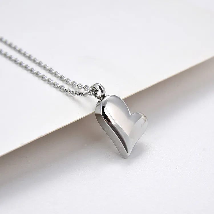 Silver curved peach heart pendant on a stainless steel necklace with extension chain