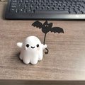 Small resin statue of a ghost walking a dog, holding a bat, for Halloween decoration.