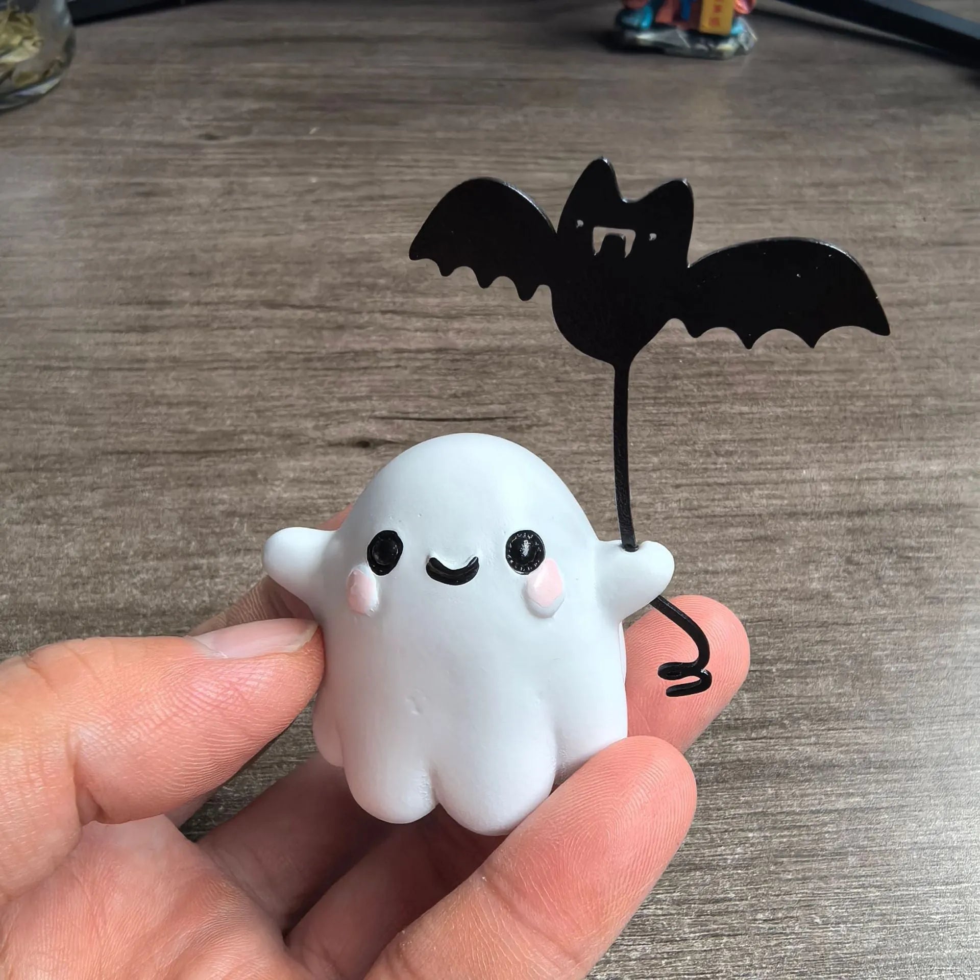 Small resin statue of a ghost walking a dog, holding a bat, for Halloween decoration.
