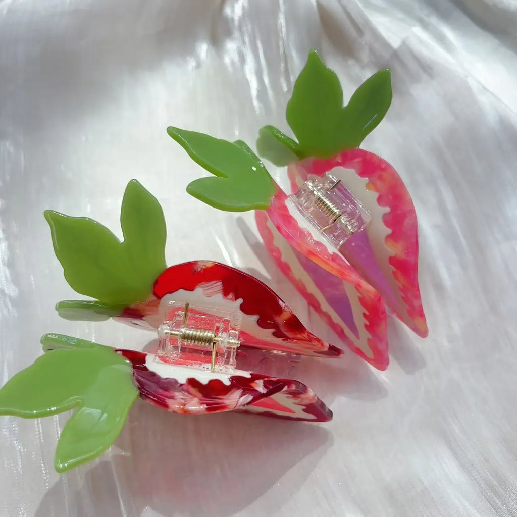 Handmade red strawberry hairpin with green leaves and a pink bow tie on a hair model.