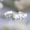 Close-up of a white alloy women's ring with a heart shape and flower opal ocean pattern detail.